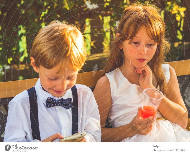 Ringträger und Blumenmädchen entspannen sich bei der Hochzeit Kinder Mädchen Technik & Technologie benutzend Smartphone Junge Glück Mobile Telefon herumhängen