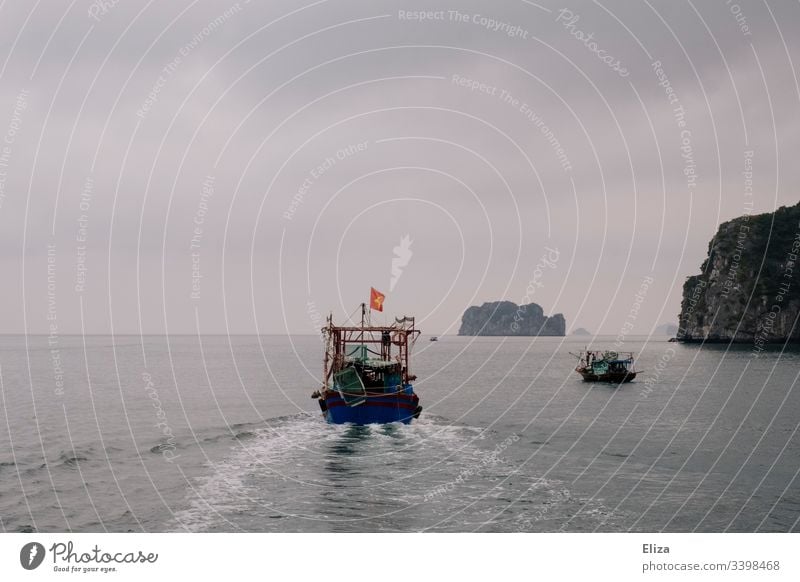 Ein Schiff auf dem Meer in der Halong Bay in Vietnam; schöne Landschaft mit Kalksteinfelsen, die aus dem Meer ragen, bei nebligem Wetter Sehenswürdigkeit Bucht