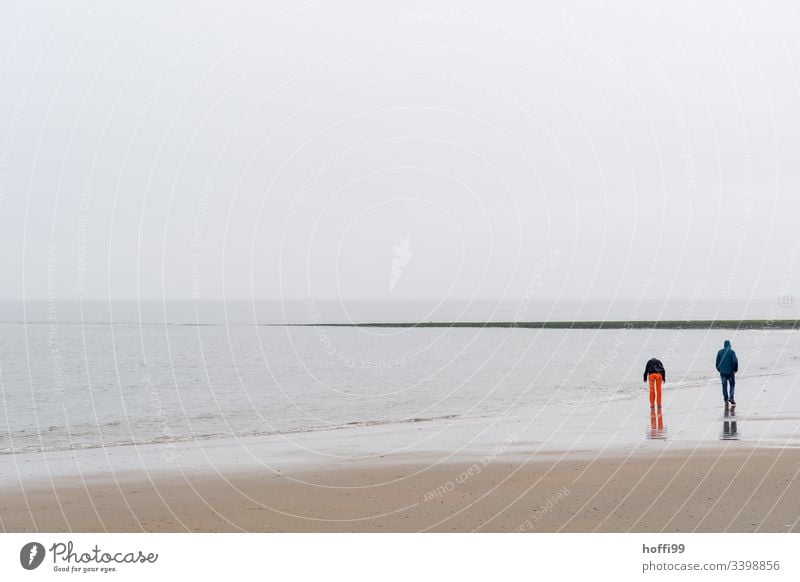 Pärchen geht im Winter bei Nebel am Strand spazieren Paar rote Hose Nordseeküste Wattenmeer Horizont Küste Insel Ferien & Urlaub & Reisen Sandstrand