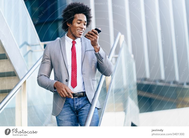 Schwarzer Geschäftsmann mit einem Smartphone in der Nähe eines Bürogebäudes schwarz lockig Afro-Look Business du Behaarung Anzug Afrikanisch männlich