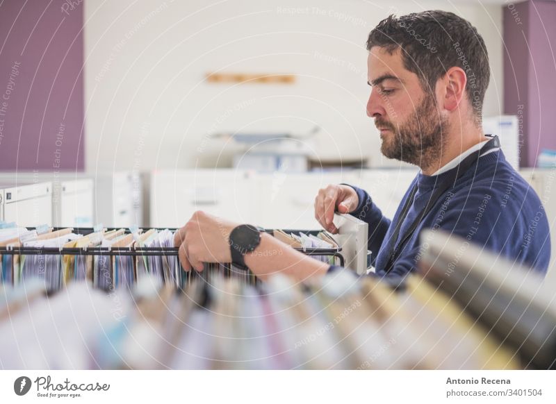 Büromitarbeiter, der im Büro Akten in der Schublade betrachtet Arbeiter Büroangestellte Mann Aktenordner wirklich Menschen Kaukasier attraktiv weiß Erwachsener