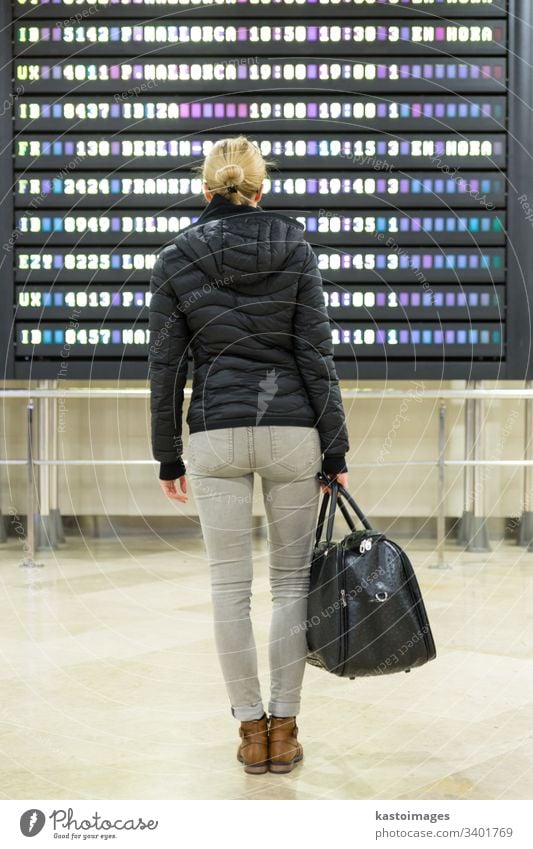 Weibliche Reisende, die eine Abflugtafel in der Flughafen-Terminalhalle kontrolliert. Anzeige Information Zeitplan reisen Ausflug Frau Fluggesellschaft Ankunft