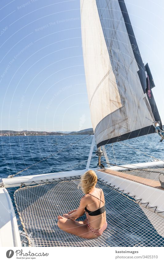 Frau entspannt sich auf einem Sommersegeltörn auf einem Luxuskatamaran in der Nähe der malerischen Stadt Palau auf Sardinien, Italien. Boot Katamaran Segeln