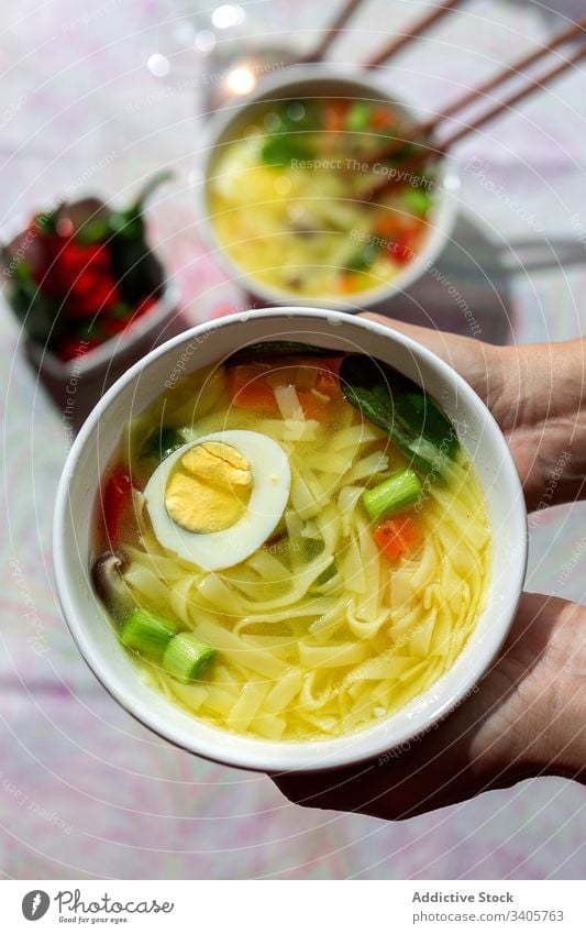 Anonyme Person, die in einem Restaurant eine Schüssel Nudelsuppe hält Lebensmittel Ramen Nudeln Suppe asiatisch Chinesisch Vegane Ernährung Gemüse Vegetarier