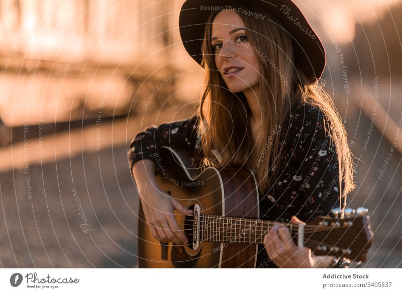 Frau spielt Gitarre auf Schienen spielen Musik reisen Stil ausführen Landschaft Instrument akustisch Musiker Gesang unterhalten Hut Boho Klang Melodie Lifestyle