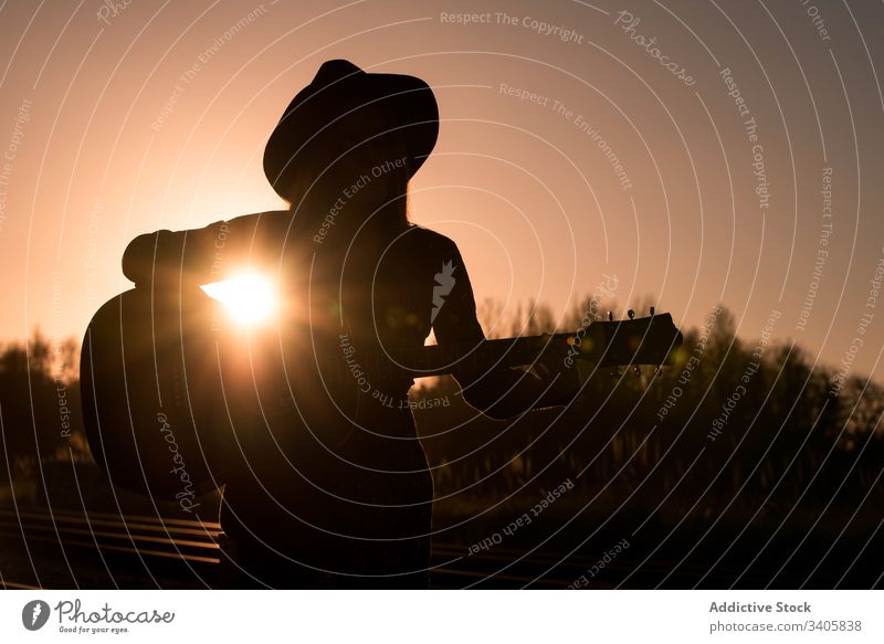 Frau spielt Gitarre auf Schienen spielen Musik reisen Stil ausführen Landschaft Instrument akustisch Musiker Gesang unterhalten Hut Boho Klang Melodie Lifestyle