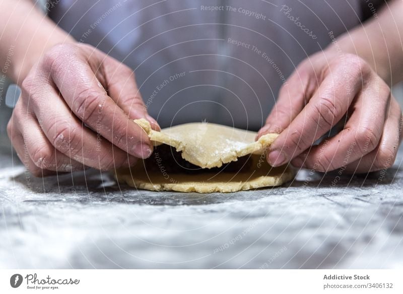 Getreidebäcker, der Marmelade zu Teig rollt Bäcker Teigwaren Koch Gebäck rollen Tisch Mehl Bäckerei Arbeit Küchenchef Lebensmittel vorbereiten frisch