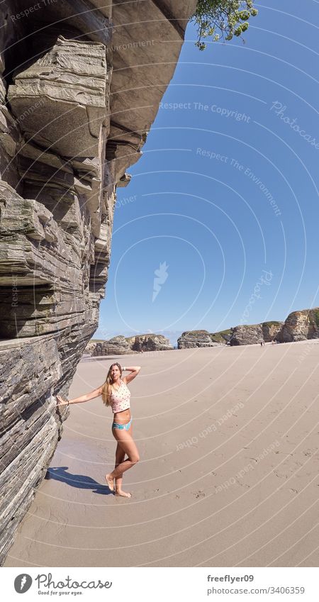 Junge Frau erklimmt sich mit einer Klippe am Strand Tourismus wandern Galicia Spanien Ribadeo Castros Illas Felsen atlantisch Bucht touristisch Kathedralen Meer