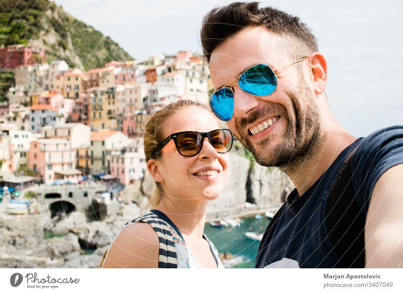 Junges Paar beim Selbstversuch in Manarola, Cinque Terre in Italien Erwachsene Freund Fotokamera Stadtbild Küste farbenfroh Europa Spaß Mädchen Freundin