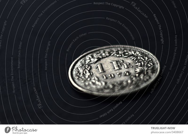 1 Schweizer Franken (SFR), silberne Münze von 1974, noch gültiges Geldstück, Stutz, schräg fotografiert vor schwarzem Hintergrund Geldmünze Währung stabil
