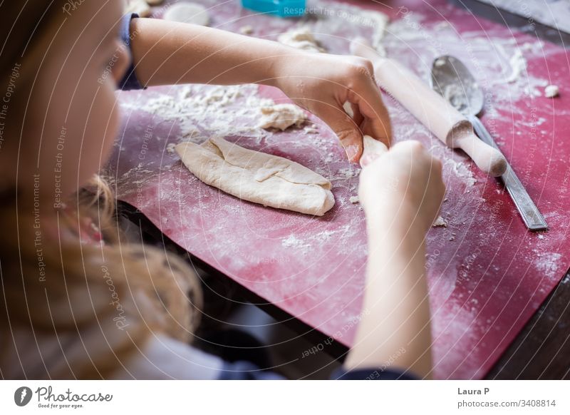 Nahaufnahme von Kinderhänden neben einem Nudelholz, die mit dem Teig spielen wüst Vorbereitung roh Küche bezaubernd niedlich süß abschließen wenig backen