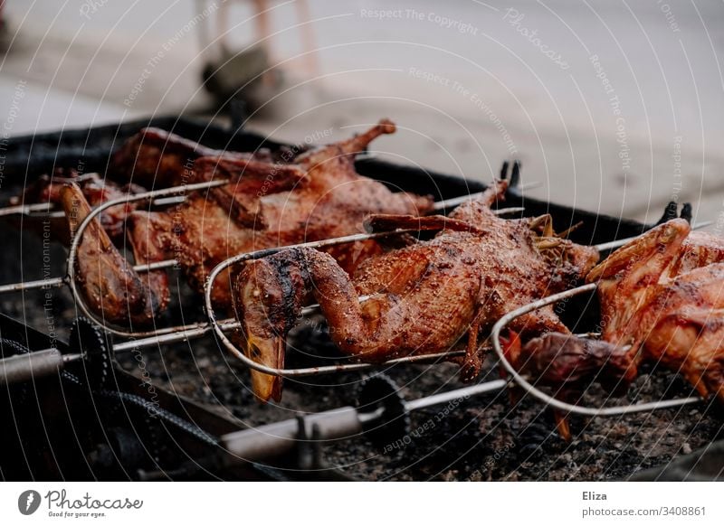 Ganze knusprig gebratene Enten am Spieß auf einem Grill gegrillt Grillspieß lecker Fleisch ESSEN Lebensmittel Farbfoto Grillrost ganz Fleischkonsum Ernährung