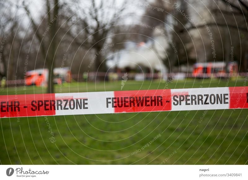 Löscharbeiten der Feuerwehr sind weiträumig mit einem Flatterband zur Feuerwehr-Sperrzone erklärt. Brand löschen Feuerwehrauto Feuerwehreinsatz Rauch Qualm