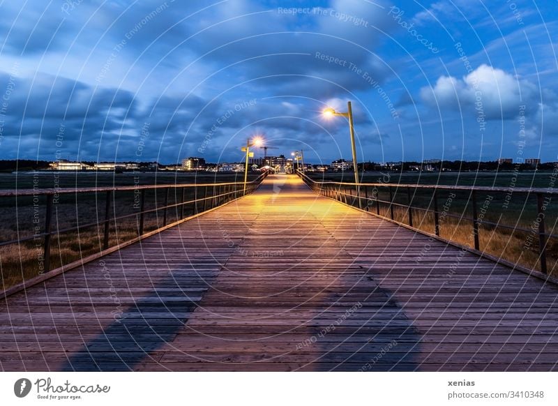 Steg in St.Peter-Ording bei Dämmerung mit großem und kleinem Schatten Holz Brücke Personen Küste blau Himmel Lampen Wolken starke Tiefenschärfe