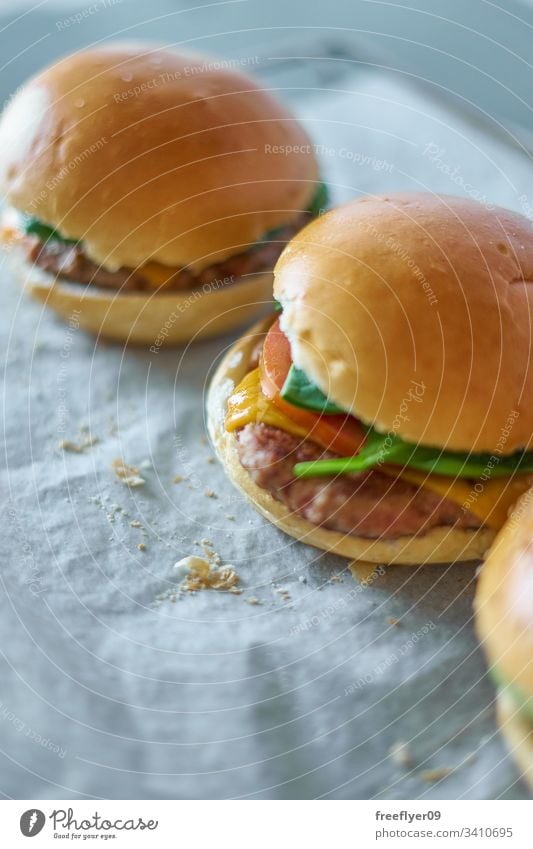 Hausgemachte Hamburger auf Backpapier selbstgemacht backen Koch Essen zubereiten Lebensmittel Gastronomie Tomate Salat Brötchen Fleisch Brot Krümel klassisch