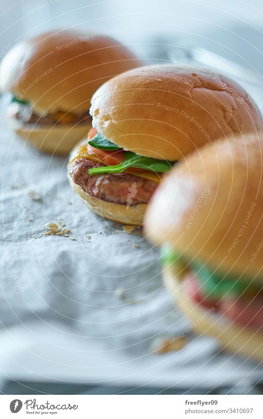 Hausgemachte Hamburger auf Backpapier selbstgemacht backen Koch Essen zubereiten Lebensmittel Gastronomie Tomate Salat Brötchen Fleisch Brot Krümel klassisch