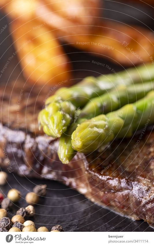 grüner Spargel auf einem Steak Rindersteak Französisch Pfeffer Pfefferkörner Porterhouse fiorentina dry aged Gemüse Kartoffel Kochen Restaurant Nahaufnahme