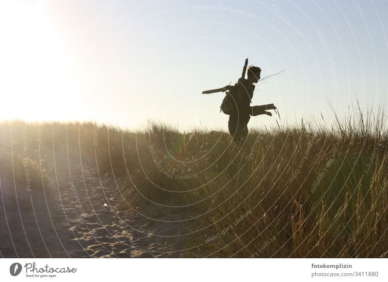 Silhouette eines jungen Manns in einer Stranddüne Feuerholz Ferien & Urlaub & Reisen Holz sammeln Abendlicht Abenteurer Abenteuer Lagerfeuer Außenaufnahme