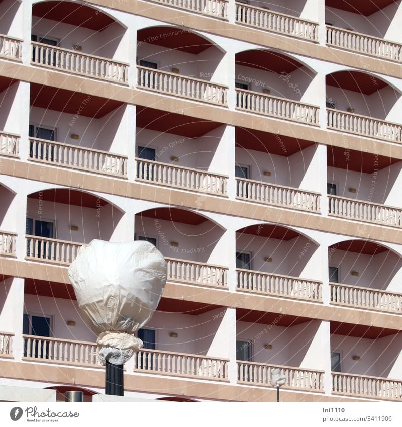 weiß "Verhülltes" mit Stange vor den Balkonen einer Hochhausfassade weiße Folie Hotelfenster Pension noch keine Saison Frühling Mallorca Terrakotta Sonnenlicht