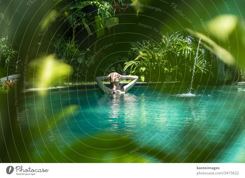 Sinnliche junge Frau entspannt sich im Infinity-Spa-Pool im Freien, umgeben von üppigem tropischem Grün in Ubud, Bali. Wellness Wasser Natur Schwimmsport