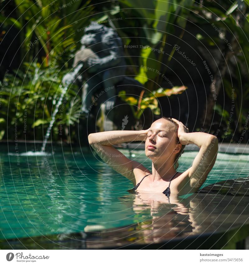 Sinnliche junge Frau entspannt sich im Infinity-Spa-Pool im Freien, umgeben von üppigem tropischem Grün in Ubud, Bali. Wellness Wasser Natur Schwimmsport