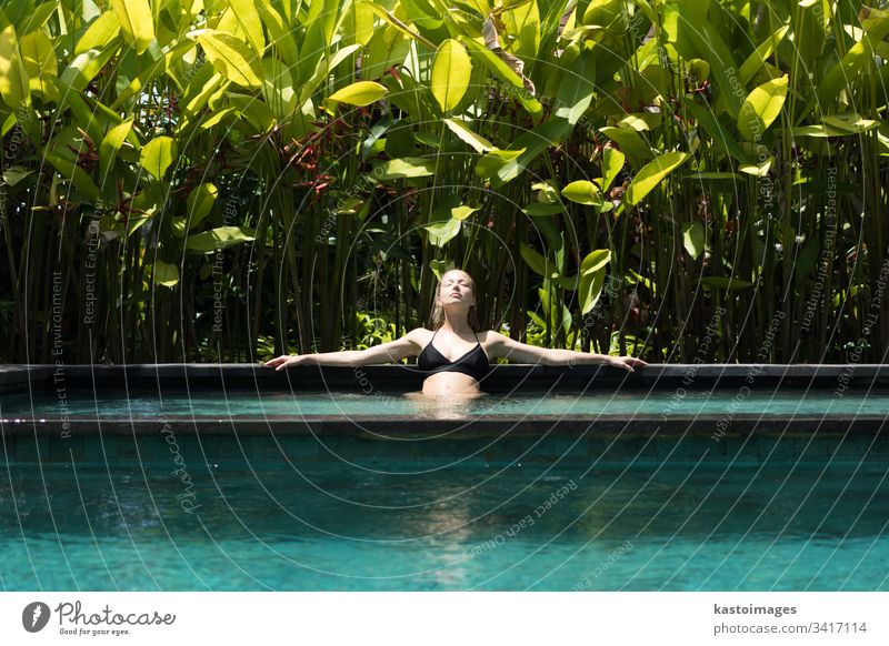 Sinnliche junge Frau entspannt sich im Infinity-Spa-Pool im Freien, umgeben von üppigem tropischem Grün in Ubud, Bali. Wellness Wasser Natur Schwimmsport