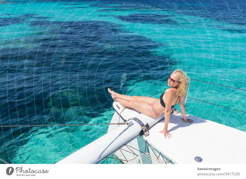 Frau entspannt sich auf einem Sommer-Segeltörn auf einem Luxus-Katamaran in der Nähe des bildschönen weißen Sandstrandes auf der Insel Spargi im Maddalena-Archipel, Sardinien, Italien.