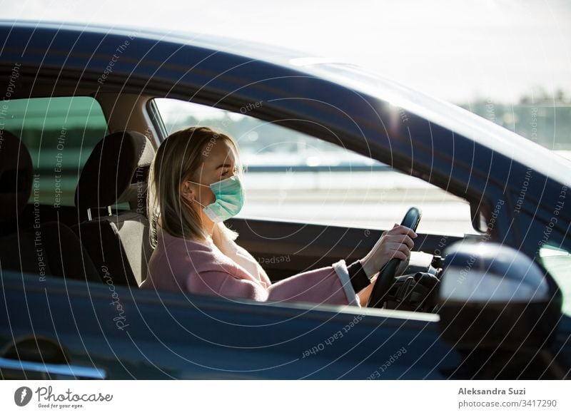 Frau mit Schutzmaske, die ein Auto auf der Straße fährt. Sicheres Reisen. Automobil Atmung PKW Großstadt Coronavirus covid-19 Armaturenbrett Ausflugsziel