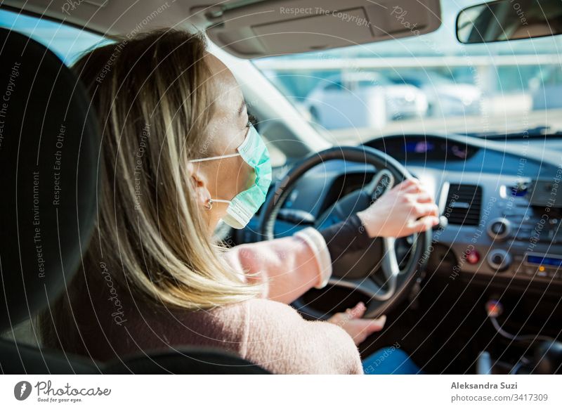 Frau mit Schutzmaske, die ein Auto auf der Straße fährt. Sicheres Reisen. Automobil Atmung PKW Großstadt Coronavirus covid-19 Armaturenbrett Ausflugsziel