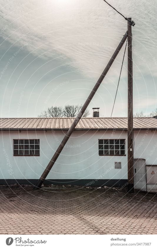 Holzdreieck vor einfachem Gebäude im Sonnenlicht Haus Fenster Dach weiß Fassade Hokz Stamm Balken Mast Stromleitung Himmel Wolken Schönes Wetter Seitenansicht