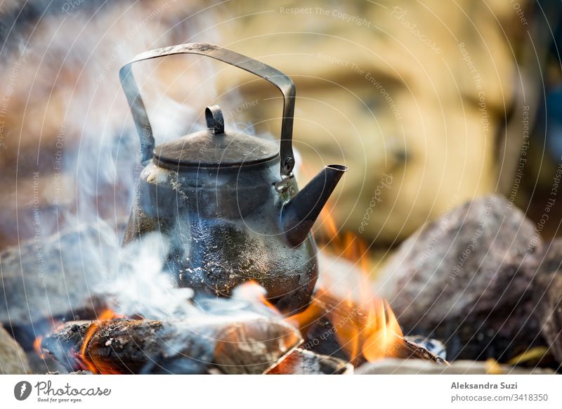 Mann und Frau machen Kaffee in einem großen Kessel am Lagerfeuer im Wald am Seeufer, machen ein Feuer, grillen. Ein glückliches Paar erkundet Finnland. Skandinavische Landschaft.