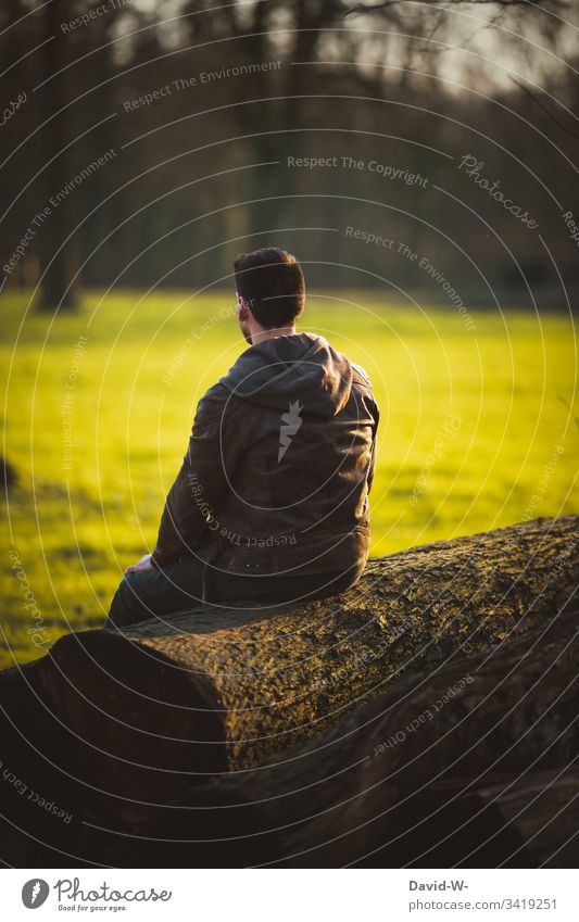 Mann sitzt alleine auf einem Baumstamm und genießt die Ruhe Mensch Natur ruhe abstand draußen einzeln Einzelgänger 1 Person eine person Herbst herbstlich