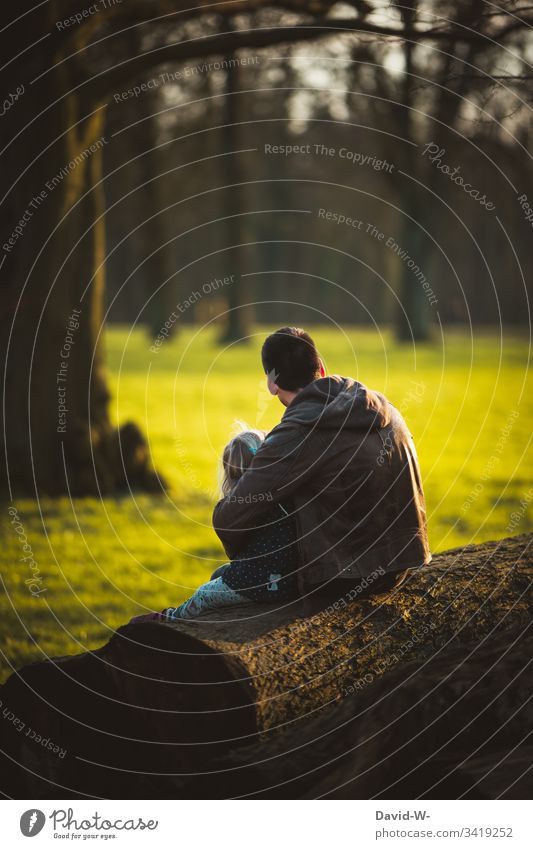 füreinander da sein Vater umarmt Kind Liebe Familie Harmonie Zusammensein Zuneigung sitzen anonym Vertrauen Natur Frühling Sonnenlicht Tochter Vater mit Kind