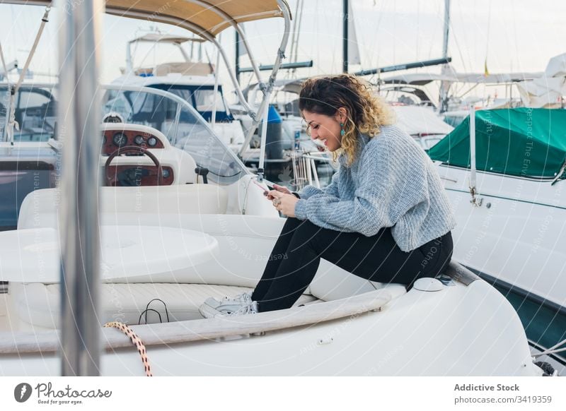 Zufriedene Dame mit Smartphone auf Yacht Frau benutzend Jacht Lächeln Browsen Handy Lachen zufrieden Inhalt genießen Surfen zuschauen Anschluss Gerät Apparatur