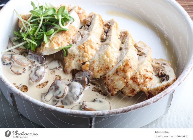 Hähnchenbrust-Rolle mit Champignons. Neben der Champignon-Sauce. Auf dunklem Hintergrund. Mit Mikrogrün dekoriert. Lebensmittel Fleisch Ostern Abendessen