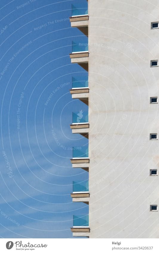 Fassade eines Hochhauses mit weißer Wand, vielen kleinen Fenstern und Balkonen an der Seite vor blauem Himmel Architektur Haus Gebäude Bauwerk Stadt Mauer