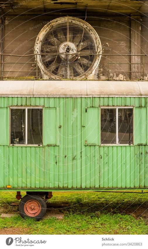 Alter grüner Bauwagen vor großem Industrieventilator Ventilator Schmutz Gras Wiese Rad rot Fenster Weltkulturerbe Völklingen