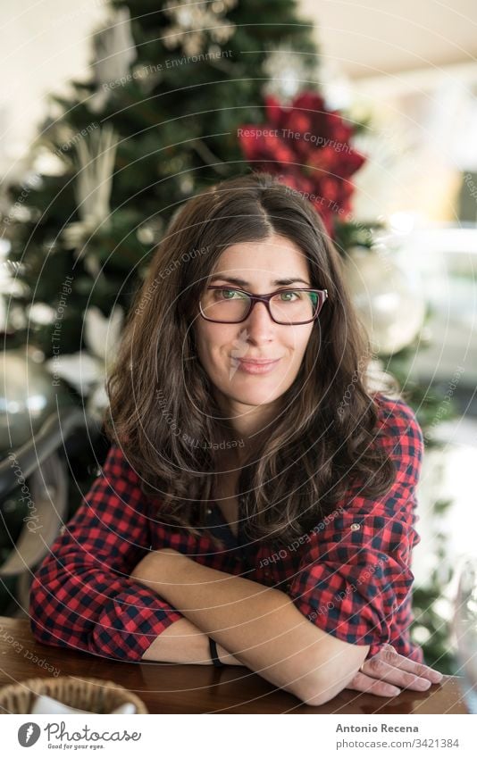 Hübsche Frau mit Brille, Porträt mit Weihnachtsbaum im Hintergrund Frauenporträt heimwärts Weihnachten 30s 40s attraktiv Kaukasier Spanisch eine Person