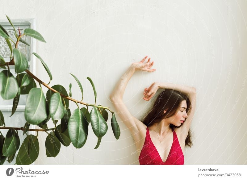 Junge Frau in roter Brünette mit den Händen an der weißen Wand, selektiver Fokus dünn schlank sexy Erwachsener Kaukasier Lifestyle Mädchen schön allein bralette