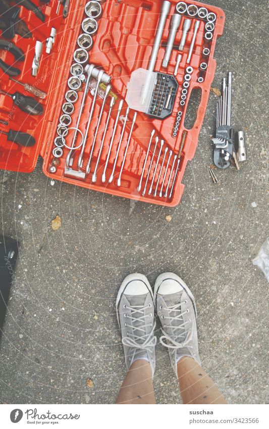 frau steht vor werkzeugskoffer Werkzeug Werkzeugskoffer Heimwerker Handwerker Heimwerkerin Beine Füße Frau Schuhe Turnschuhe Schraubenschlüssel Schraubenzieher