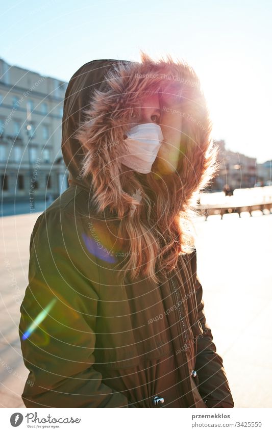 Mädchen, das die Gesichtsmaske trägt, um eine Virusinfektion zu vermeiden und die Ausbreitung der Krankheit zu verhindern. Junge Frau, die im Stadtzentrum spazieren geht. Schutz vor einer Virusinfektion. Echte Menschen, authentische Situationen