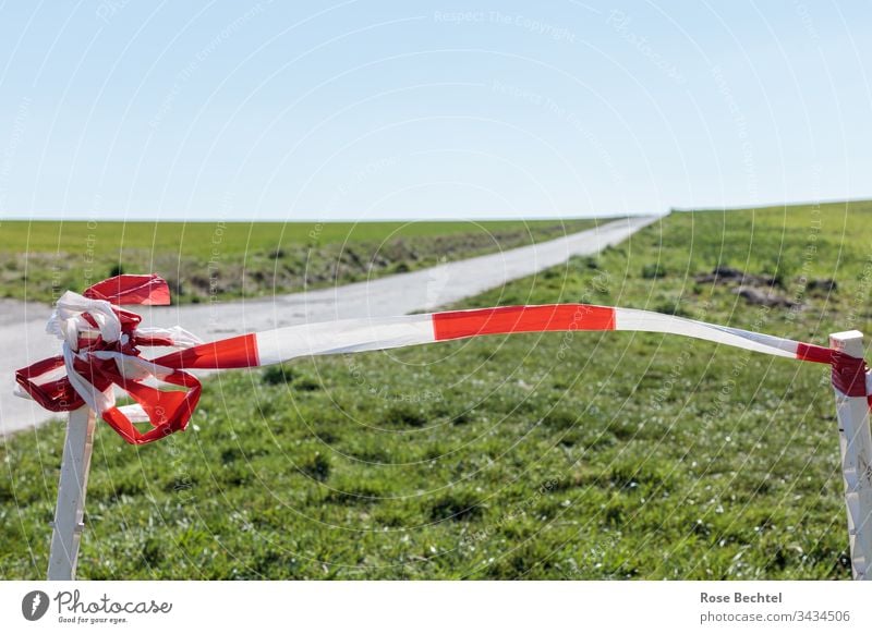 Wiesen und Feldweg mit rotweißen Absperrband Absperrung Außenaufnahme Farbfoto Menschenleer Tag feldweg grün Landschaft Wolkenloser Himmel Textfreiraum oben