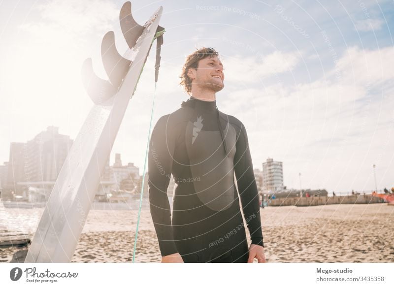 Surfer, der am Strand neben seinem Surfbrett steht. Mann Brandung Wasser Sport Surfen MEER Meer im Freien sportlich Küstenlinie Wellen Hintergrund Abenteuer