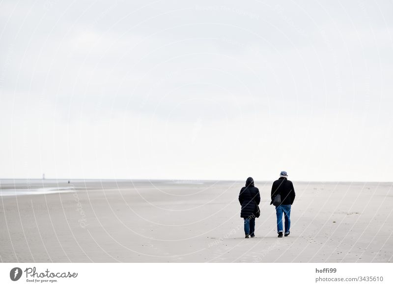 Strandspaziergang im Winter pärchen Sand Sandstrand Paar Nordseeküste Wattenmeer Ferien & Urlaub & Reisen Insel seichtes Wasser Küste Horizont Brandung