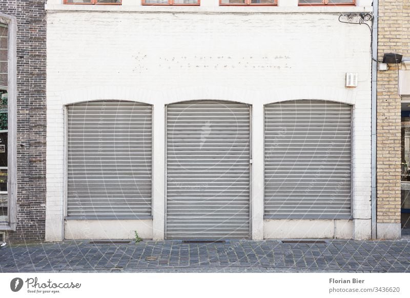 Geschlossenes Ladengeschäft mit herunter gelassenen Rolläden in einer altertümlichen Fassade Geschäft geschlossen Rolladen Krise Fenster Tür Einzelhandel