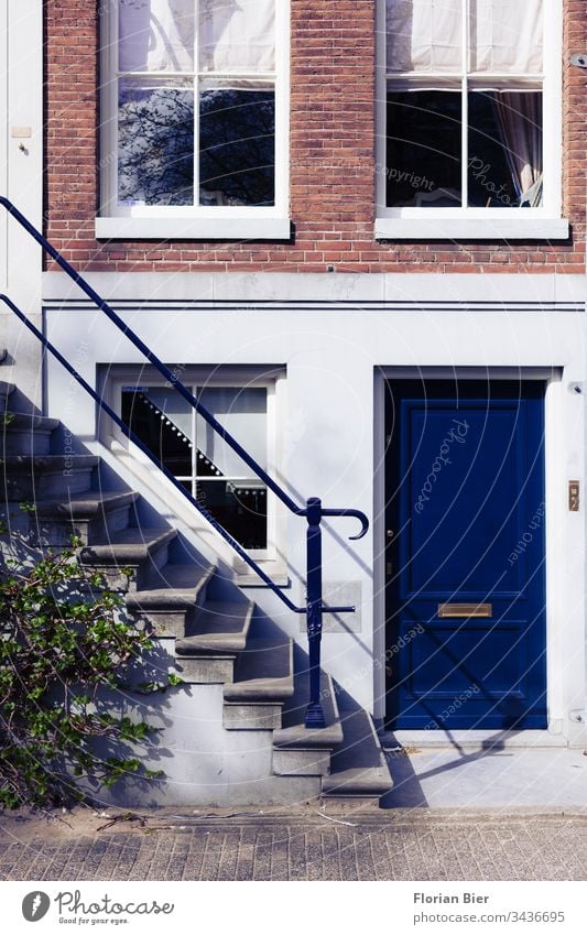 Eingang eines Wohnhauses mit einer kräftig blauen Eingangstür im Amsterdamer Krachtenviertel Niederlande Haus Fenster Fassade Victorianisch Baustil Gebäudeteil