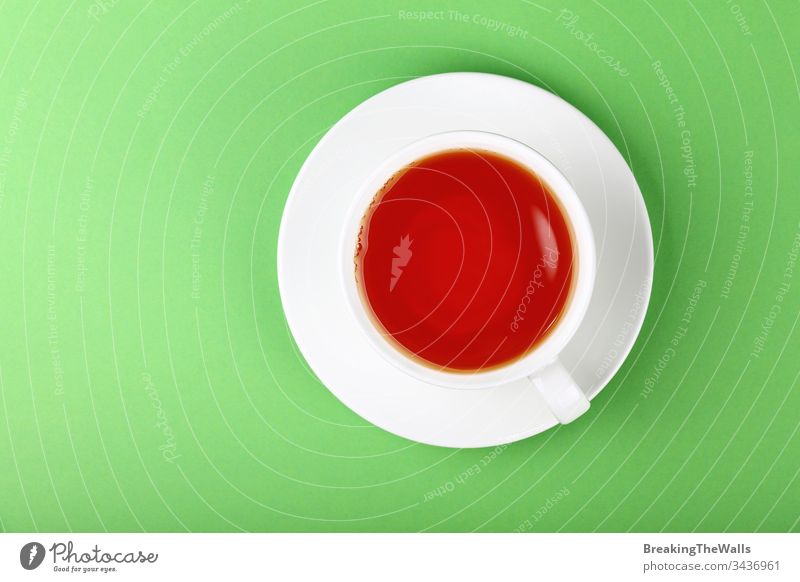 Weiße Tasse schwarzer oder roter Früchtetee über grünem HINTERGRUND Tee Frucht Aufguss weiß Untertasse Papier Pastell Hintergrund Nahaufnahme erhöht Top Ansicht