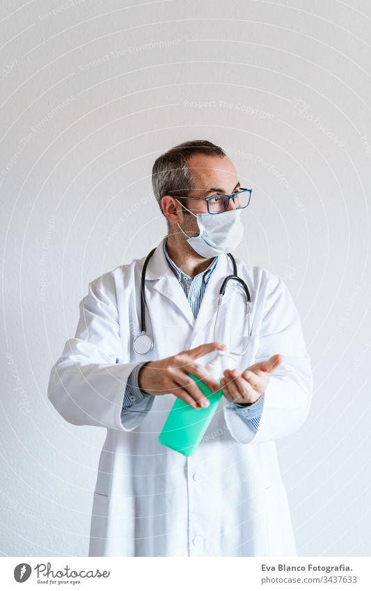 Ein Arzt, der im Haus eine Schutzmaske trägt. Er hält ein Alkoholgel oder ein antibakterielles Desinfektionsmittel in der Hand. Hygiene- und Coronavirus-Konzept. Covid-19