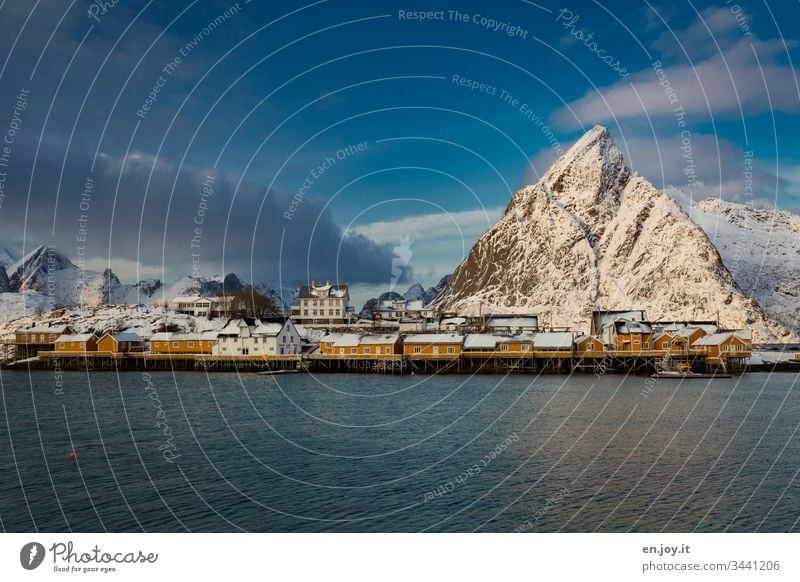 Kleines Fischerdorf am Fjord vor verschneiten Bergen zum Sonnenuntergang Türkis Blau Panorama (Aussicht) Insel Aussicht auf Stadt Sakrisøy Weitwinkel