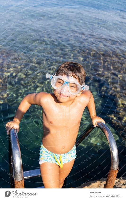 Kleiner Junge auf einer Badeleiter, der zum Baden ins Meer hinuntergeht amandakis schön blau Kind Kindheit übersichtlich Klettern Küste Kristalle niedlich